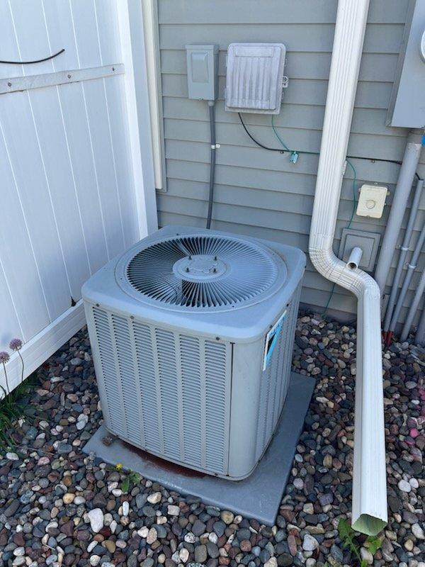 Responded to no cooling complaint on an 8-year-old residential air conditioning system. Upon arrival, found the outdoor condenser unit humming but not operating properly with warm copper lines and air blowing from the top of the unit. Diagnosed a failed capacitor preventing proper compressor operation. Verified air filter was clean and condensate drain line was clear. Replaced the defective capacitor and performed condenser coil cleaning to remove accumulated debris. Started the system and verified proper operation with refrigerant pressure testing, measuring approximately 8.5 degrees subcooling which falls within acceptable parameters. Confirmed thermostat communication with equipment and verified adequate airflow from indoor unit. System restored to normal cooling operation.