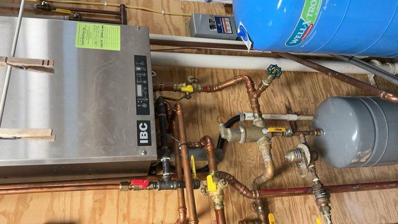 Completed comprehensive plumbing inspection and evaluated water softener system experiencing salt accumulation and water leakage issues. Inspected mechanical room heating system, copper piping network with multiple valves and connections, expansion tank, and pressure tank assembly. Documented shower area with dual tiling patterns and drainage system during inspection process.