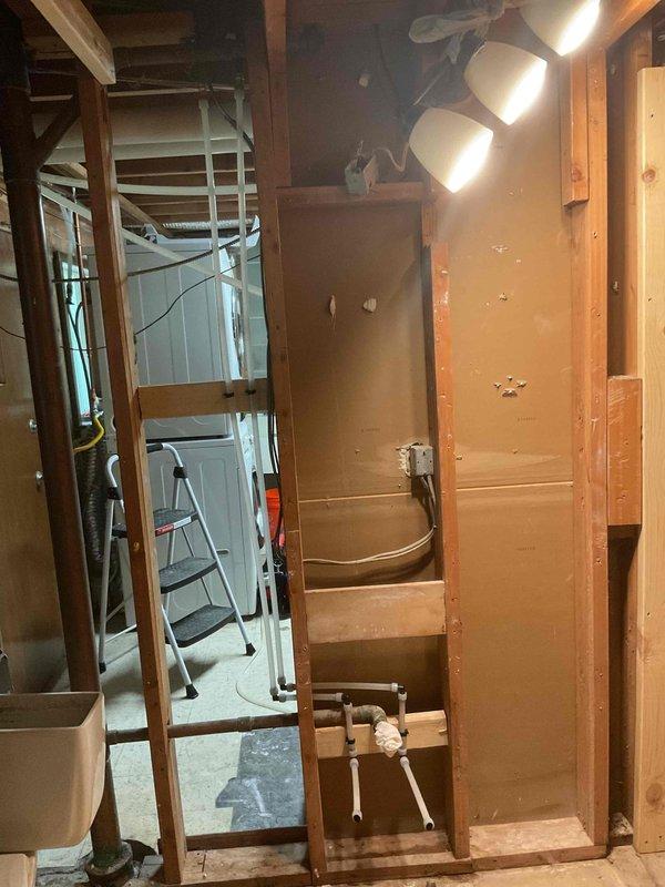 Responded to emergency call for frozen pipe burst that caused basement flooding. Assisted with temporary rough-in plumbing work in affected area, including removal and disposal of damaged existing piping. Performed comprehensive rough-in installation throughout multiple rooms including bathroom, laundry room, and mechanical room. In bathroom, rebuilt vanity drain and DWV system, installed ADA-compliant toilet, and installed customer-supplied tub with shower valve, spout, and head. In laundry area, installed washing machine valve, rebuilt laundry tub drain, and installed deck-mount faucet. In mechanical room, installed freeze-proof hose bibb with up to 15 feet of PEX tubing, installed new water main with shutoffs as required up to 50 feet, and completed associated rough-in work. Pulled baseboard covers in bedroom, laundry room, and bathroom to access work areas. All work completed and inspected per code requirements.