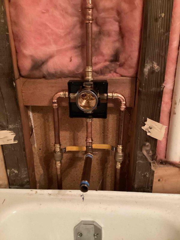 Completed bathroom plumbing installation in a condo unit including shower valve replacement with new isolation valves, toilet installation, and shower trim finishing. Lavatory faucet installation encountered issue with defective hot water valve requiring replacement parts to be sourced. Successfully installed new shower valve assembly with copper supply lines and shutoff valves during bathroom renovation phase, coordinating with building-wide water shutoff requirements.