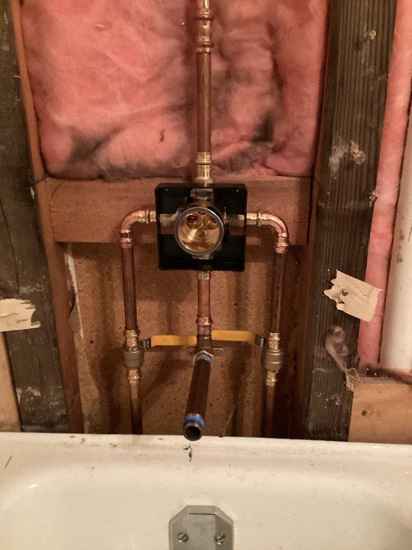 Completed bathroom plumbing installation in a condo unit including shower valve replacement with new isolation valves, toilet installation, and shower trim finishing. Lavatory faucet installation encountered issue with defective hot water valve requiring replacement parts to be sourced. Successfully installed new shower valve assembly with copper supply lines and shutoff valves during bathroom renovation phase, coordinating with building-wide water shutoff requirements.
