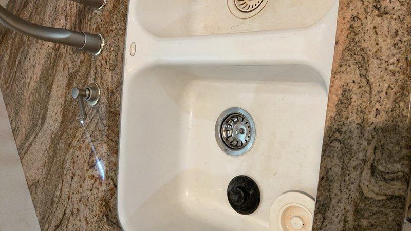 Responded to service call for non-functioning garbage disposal in kitchen. Upon inspection, determined disposal unit was inoperable and required replacement. Removed existing garbage disposal and installed new sink basket assembly in white double-basin kitchen sink with granite countertop. Verified proper drainage and tested all connections for leaks. Completed installation of disposal flange and strainer assemblies in both basins, ensuring secure mounting and proper seal. All fixtures left in working order with no drainage issues detected.
