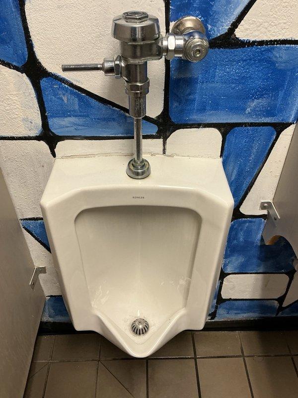 Responded to service call for clogged wall-mounted Kohler urinal that would not drain. Upon arrival, found unit already marked out of service. Applied chemical drain treatment (Sizzle) and agitated the blockage to restore proper drainage. Verified flush valve operation and confirmed urinal returned to normal function.