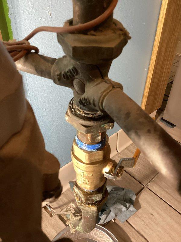 Responded to callback for leak at meter condensate piping. Upon arrival, identified leak at lower meter horn union where condensate drain was running backwards. Disassembled and cleaned union connection, reseated components to ensure proper seal. Installed 45-degree fitting to redirect condensate drainage and prevent backflow into union. Tested system operation and confirmed leak was resolved with proper drainage flow established. Documented repairs with photos showing valve assembly and floor drain installation area.