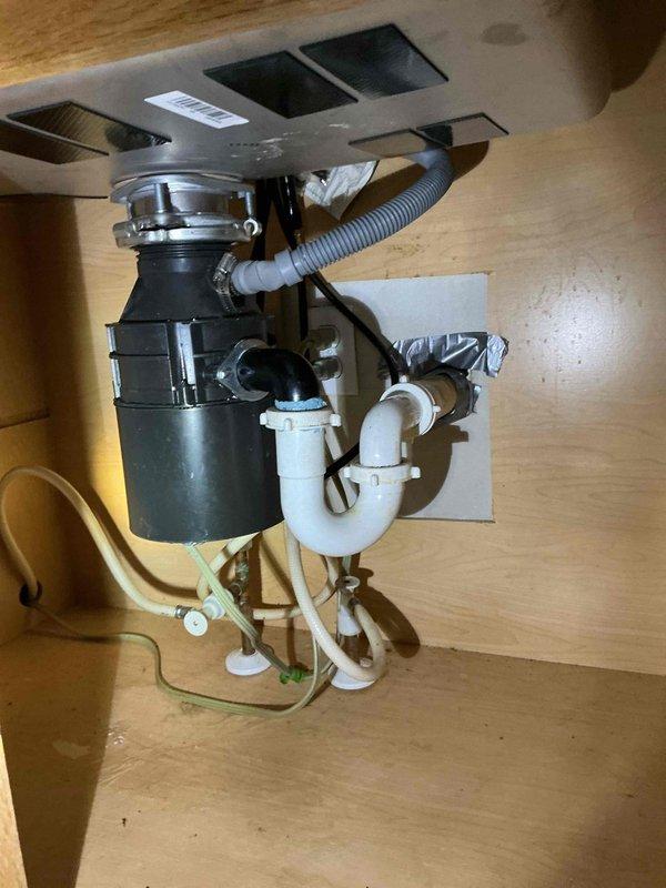 Completed kitchen sink replacement, transitioning from a double basin to a customer-supplied Kohler single basin undermount sink with integrated drying rack. Disconnected and removed existing faucet with side sprayer, garbage disposal, and PVC drain lines before extracting the old double basin sink. Installed customer-supplied single handle kitchen faucet with pull-down sprayer featuring coiled spring neck design and connected to existing water supply lines. Reconnected garbage disposal unit to new sink configuration and modified PVC drain assembly, including P-trap, to accommodate the change from double to single basin layout. Verified all plumbing connections for proper operation and leak-free performance, sealed perimeter of sink to countertop, and confirmed garbage disposal and faucet functionality. One-year workmanship warranty provided on installation.