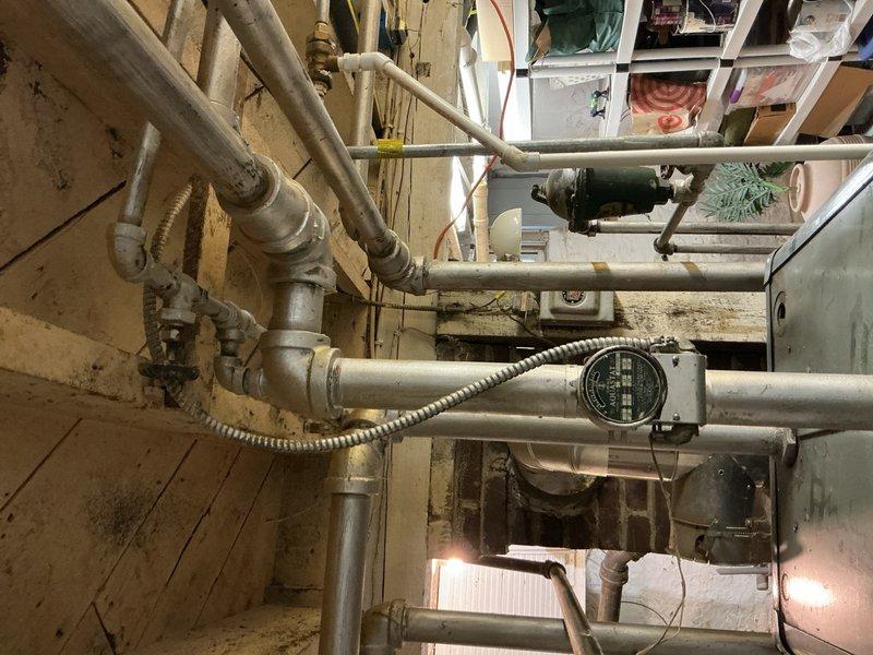 Completed comprehensive plumbing inspection of residential property identifying multiple deficiencies requiring attention. Inspected water heater and confirmed missing temperature and pressure relief valve as noted in previous home inspection report. Evaluated basement utility area plumbing system including supply lines, drainage components, and mechanical equipment connections. Assessed floor drain performance issues related to washing machine discharge, noting inadequate drainage capacity. Inspected kitchen plumbing and identified missing proper venting for drain system. Examined bathroom sink trap assembly and determined replacement needed due to improper configuration or deterioration. Documented all findings with photographic evidence showing pipe routing, fixture installations, and mechanical equipment conditions for repair recommendations and future reference.