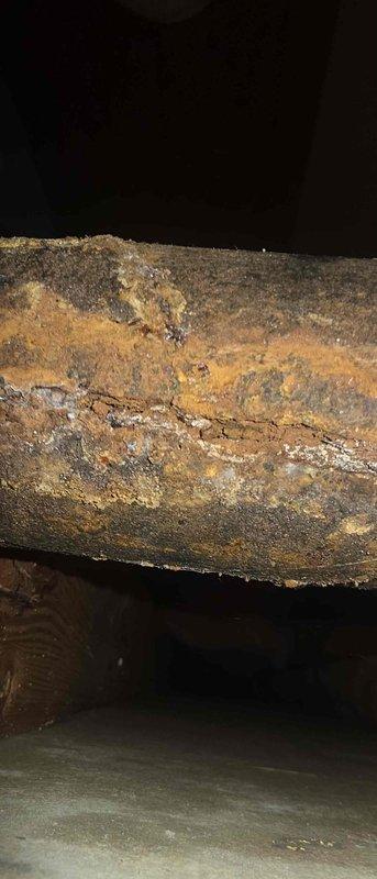 Diagnosed and assessed severely corroded cast iron mission band pipe system showing extensive rust damage and structural compromise. The existing pipe exhibited heavy oxidation with flaking layers and visible cracking throughout the affected section. Documented the deteriorated condition of the horizontal pipe run in the crawl space area, noting the advanced corrosion that had penetrated through multiple layers of the metal surface. Provided repair estimate for replacement of the compromised cast iron section with updated plumbing materials to restore proper function and prevent potential failure or water damage.