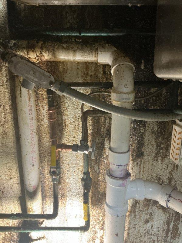 Responded to water leak emergency at property. Upon arrival, investigated reported leak on main water line. Initial assessment indicated potential issue with water line connection off main pipes or coupler joint at water main itself. 

Conducted thorough inspection of utility area and traced leak source to hot water supply line located beneath wash sink. Identified compromised section of copper piping as cause of active leak. Leak was not at main water line as initially suspected, but rather isolated to hot side plumbing under sink.

Shut off water supply to affected area and removed damaged copper pipe section. Measured and cut replacement copper piping to proper specifications. Installed new copper section using appropriate fittings and connections. Soldered joints to ensure watertight seal. Restored water supply and pressure tested repair to verify no additional leaks present.

Inspected surrounding plumbing infrastructure in utility space, noting existing PVC drainage lines, variou