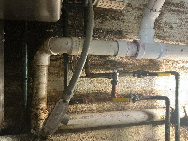 Responded to water leak emergency at property. Upon arrival, investigated reported leak on main water line. Initial assessment indicated potential issue with water line connection off main pipes or coupler joint at water main itself. 

Conducted thorough inspection of utility area and traced leak source to hot water supply line located beneath wash sink. Identified compromised section of copper piping as cause of active leak. Leak was not at main water line as initially suspected, but rather isolated to hot side plumbing under sink.

Shut off water supply to affected area and removed damaged copper pipe section. Measured and cut replacement copper piping to proper specifications. Installed new copper section using appropriate fittings and connections. Soldered joints to ensure watertight seal. Restored water supply and pressure tested repair to verify no additional leaks present.

Inspected surrounding plumbing infrastructure in utility space, noting existing PVC drainage lines, variou