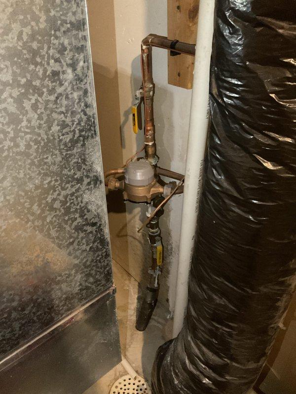 Completed comprehensive plumbing inspection of residential property with focus on water heater and main water supply system. Inspected Rheem water heater unit located in basement utility area, verifying proper installation, connections, and operational status. Examined backflow preventer assembly with dual isolation valves on main water supply line, confirming proper function and compliance with code requirements. Documented all findings with photographs for service records.