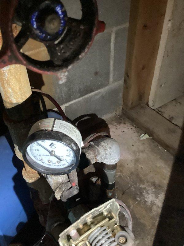 Responded to service call for leaking pressure tank in basement utility area. Upon inspection, confirmed active leak from aging blue pressure tank showing significant deterioration, surface corrosion, and wear. Water staining and rust-colored marks visible on concrete floor beneath equipment, indicating ongoing moisture exposure. Pressure tank exhibited compromised integrity requiring full replacement. Documented existing conditions including tank specifications, current pressure readings from mounted gauge, and plumbing connections to water softener and water heater systems. Photographed deteriorated tank exterior, tank tee assembly, and associated piping infrastructure. Submitted part order form to obtain estimate for new pressure tank and tank tee assembly replacement. Customer advised that water supply did not require emergency shutoff at time of inspection.