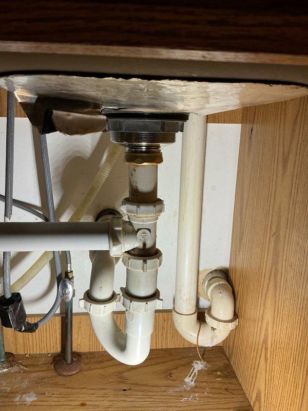 Responded to call for water leak underneath kitchen sink. Upon inspection, identified failed basket strainer assembly as source of leak. Given the age of the home (built in 1987) and appearance of original plumbing components, the existing basket strainer had deteriorated beyond serviceable condition. Removed old basket strainer assembly, cleaned mounting surface and sink drain opening, and installed new basket strainer with proper sealing gasket and compression fittings. Verified all connections were secure and tested system under full water pressure to confirm leak was eliminated. Existing P-trap and drain assembly remained functional and were left in place.