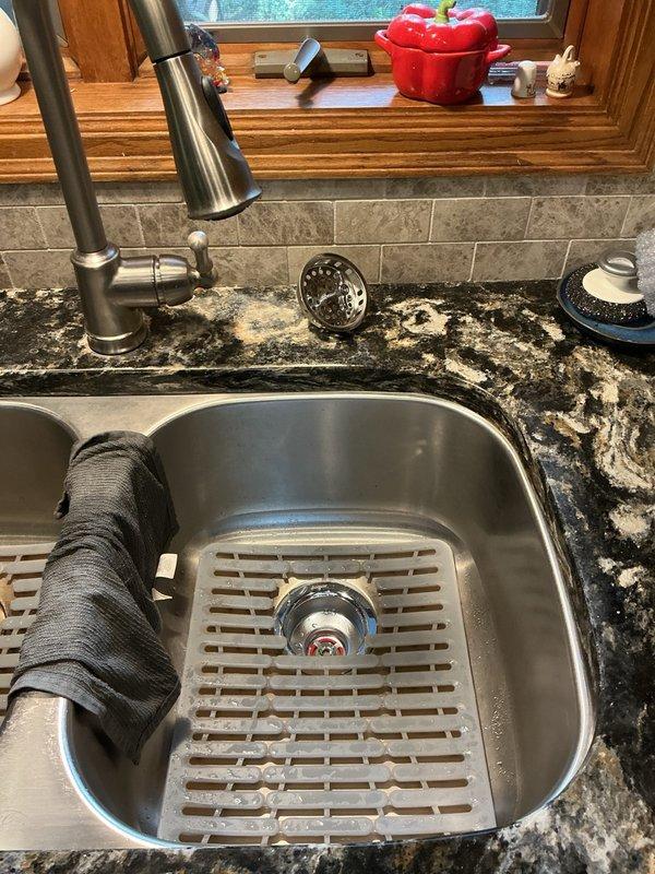 Responded to call for water leak underneath kitchen sink. Upon inspection, identified failed basket strainer assembly as source of leak. Given the age of the home (built in 1987) and appearance of original plumbing components, the existing basket strainer had deteriorated beyond serviceable condition. Removed old basket strainer assembly, cleaned mounting surface and sink drain opening, and installed new basket strainer with proper sealing gasket and compression fittings. Verified all connections were secure and tested system under full water pressure to confirm leak was eliminated. Existing P-trap and drain assembly remained functional and were left in place.