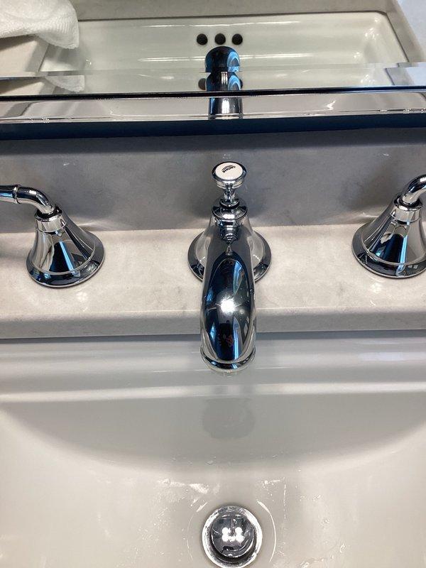 Responded to callback for widespread bathroom faucet that had become unstable following previous repair attempt. Upon inspection, found the three-piece chrome faucet assembly lifting away from granite countertop surface with worsening alignment issues. Properly tightened and secured all three components of the widespread faucet installation, including both handle valves and center spout, ensuring proper mounting to countertop. Discussed replacement fixture options with customer for future consideration.