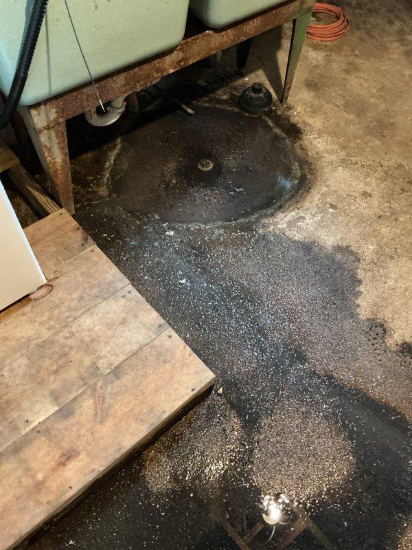Responded to kitchen drain backup causing water to surface through basement floor drain. Upon arrival, jetted the entire kitchen drain line to clear the blockage and perform diagnostic assessment. Investigation revealed the bottom section of the drain pipe had completely rotted out and required replacement.

Relocated laundry tub, washing machine, and dryer to access the affected area. Broke out concrete flooring to expose the deteriorated drain line. Removed the failed pipe section and installed new 2" PVC drain pipe, making all necessary connections to the existing drainage system. Properly bedded the new pipe with sand for stability and support. Backfilled the excavation and poured new concrete to restore the floor surface. Conducted operational testing to verify proper drainage function and confirm the repair resolved the backup issue.