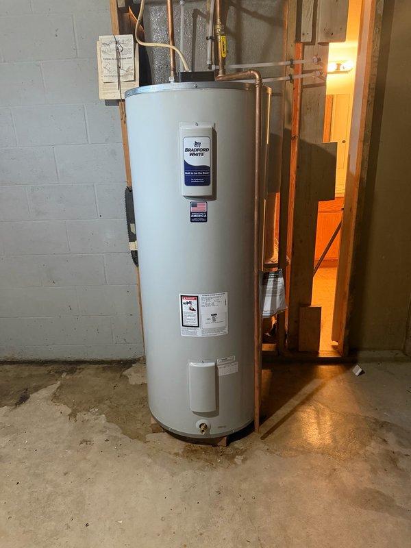 Completed installation of an 80-gallon Bradford White electric water heater designed for light-duty commercial applications with intermittent hot water loads. Unit features adjustable thermostat with temperature range of 120° to 181°F, manual reset high temperature cutoff, and COREGARD™ anode rods with stainless steel core for extended tank protection. 

Installed water heater in basement utility room on concrete floor against cinder block wall. Connected copper supply piping to top of unit and installed temperature and pressure relief valve with proper discharge pipe running down side of tank. Verified all plumbing connections are secure and leak-free. Ensured unit meets standby loss requirements of U.S. Department of Energy and current ASHRAE/IES 90.1 standards. Installation includes 6-year limited tank warranty and all applicable permits were obtained for the work performed.