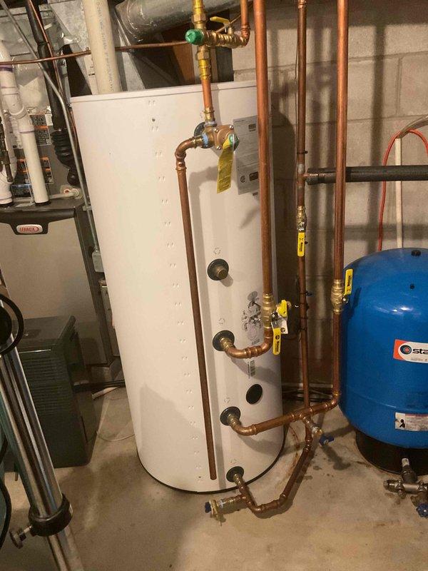 Completed comprehensive plumbing inspection of residential mechanical room, examining water heater, pressure tank, and associated copper piping systems with brass fittings and safety valves. Documented current condition of all plumbing components, connections, and equipment for maintenance records, with particular attention to piping age assessment and system integrity.