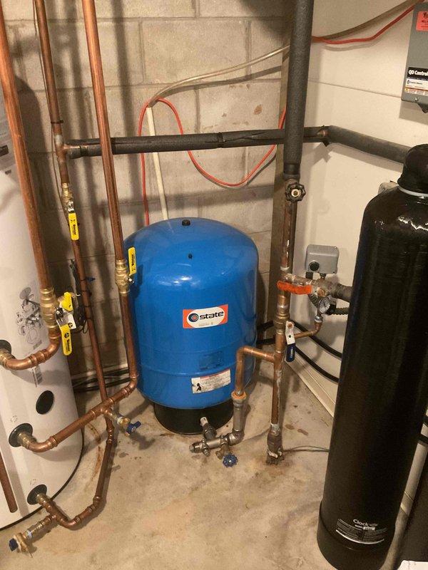 Completed comprehensive plumbing inspection of residential mechanical room, examining water heater, pressure tank, and associated copper piping systems with brass fittings and safety valves. Documented current condition of all plumbing components, connections, and equipment for maintenance records, with particular attention to piping age assessment and system integrity.