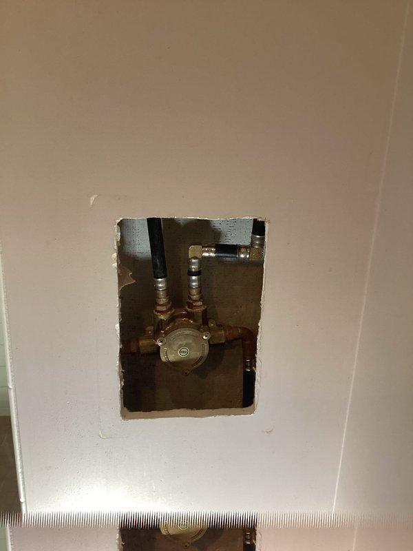 Responded to no hot water call and discovered shower valve cartridge failure preventing cold water flow. Accessed wall cavity to expose brass valve assembly and backflow preventer. Diagnosed faulty cartridge requiring replacement and sourced appropriate new cartridge to restore proper hot and cold water mixing function.
