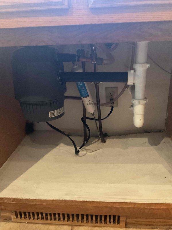 Completed garbage disposal installation at a single-family residence using customer-supplied unit. Mounted disposal unit beneath kitchen sink, connected to existing drain line with P-trap configuration, and established electrical connection via existing outlet in sink cabinet. Installation included proper mounting bracket assembly, drainage connections to white PVC plumbing system, and verification of operational functionality. All components secured and tested successfully.