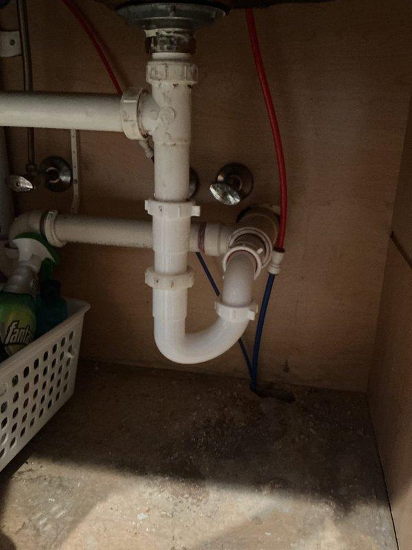 Responded to service call for leaking reverse osmosis system with water pouring from blue drain hose connection point. Replaced defective P-trap assembly and reconnected RO drain line to eliminate leak. Installed new drain components to restore proper function and prevent future water damage beneath sink.