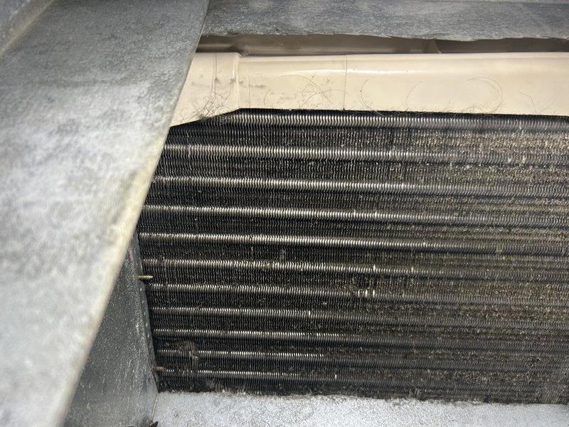 Responded to no cooling complaint with system freezing up. Upon inspection, found heavily soiled evaporator coil, blower wheel, and secondary drain pan with significant dust and debris accumulation, contrary to initial report that coil was clean. Performed thorough cleaning of evaporator coil, blower wheel, and secondary drain pan to restore proper airflow. After cleaning, connected manifold gauges and tested system operation. Unit now operating without freezing, providing adequate cooling. System appears slightly low on refrigerant charge but is functional. Homeowner elected to monitor system performance and defer refrigerant charge at this time.