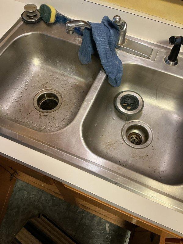 Responded to kitchen sink backup affecting dishwasher and garbage disposal in townhome unit. Upon arrival, found water accumulating in both the sink basin and dishwasher due to shared drainage system backup. Performed diagnostic assessment and determined blockage was located 10 to 15 feet downstream in the drain line.

Utilized drain cable to clear obstruction, breaking up accumulated soap scum, solidified chemical drain cleaner residue, and food debris causing the stoppage. Mechanically removed blockage material through cabling process. Flushed drain line thoroughly with sink water to ensure complete removal of debris and verify proper flow rate. Reassembled all drain components and conducted operational testing of the system.

Verified kitchen sink drains freely with no standing water, dishwasher connection draining properly, and garbage disposal operating without backup. All fixtures restored to normal function at time of completion.