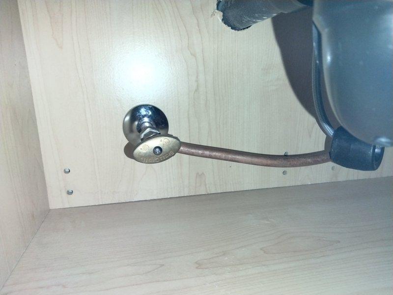 Responded to callback regarding kitchen and bathroom shutoff valve replacement following previous leak repair service. Inspected kitchen sink cabinet plumbing assembly, including copper supply lines, chrome shutoff valves, black PVC P-trap configuration, and stainless steel drain basket strainer. Documented existing valve conditions under kitchen sink with two chrome shutoff valves mounted on back panel with black flexible supply lines. Also assessed bathroom shutoff valve requiring replacement. Confirmed availability of necessary valve replacement parts and provided estimates for shutoff valve replacement work at both locations for customer consideration.