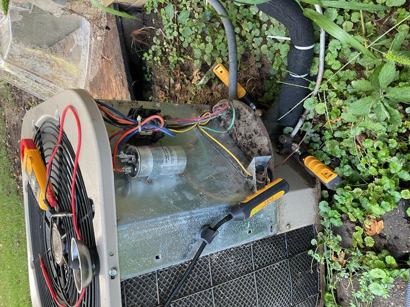 Responded to no-cooling complaint on ThermalZone outdoor condensing unit at residential property where new homeowner reported system failed to reach setpoint after initial 8-hour operation. Performed diagnostic evaluation on unit with missing model/serial data plate, preventing exact age verification. Measured incoming voltage at 246V and tested dual run capacitor rated 30/5 µF, which measured 29.5/5 µF within acceptable tolerance. Verified all wiring connections to compressor and condenser fan motor. Upon thermostat call for cooling, observed condenser fan motor energized but fan blade assembly exhibited extreme stiffness requiring manual assistance to rotate, indicating failed condenser fan motor with seized bearings rather than capacitor failure. Advised homeowner that unit appears to be legacy R-22 equipment based on age and configuration, complicating repair decisions due to refrigerant obsolescence. Discussed implications of planned backyard project requiring potential condenser 