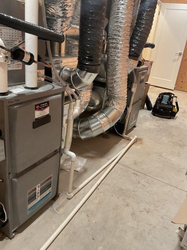 Performed annual maintenance on dual HVAC systems including two furnaces, two air conditioners, two humidifiers, and air exchanger. Adjusted gas manifold pressures on both furnaces from 11" to under 10" water column to manufacturer specifications. Corrected excessive temperature rise on main floor furnace from 75°F to 60°F by increasing blower speed; upstairs unit operating at acceptable 55°F rise. Replaced both 16x20x1 filters and verified flame sensor operation at approximately 50 ohms. Installed missing combustion box blocker plate in manifold that was omitted during original installation. Checked subcooling and superheat on both air conditioning units and documented with photos. Identified incorrect 24V wiring on both humidifier controls; recommended contacting original installer for warranty correction as units are less than one year old. Observed oil accumulation on refrigerant lines at press fittings on left AC unit, indicating potential refrigerant leak requiring follow-up insp