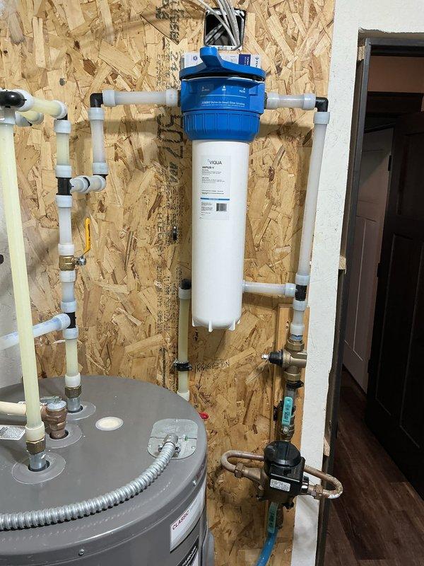 Installed whole home water filtration system with new carbon filter unit mounted to utility room wall. Connected filtration system to existing plumbing infrastructure using PVC piping, integrated with water heater supply line, and verified proper operation of all shut-off valves and pressure regulation components.