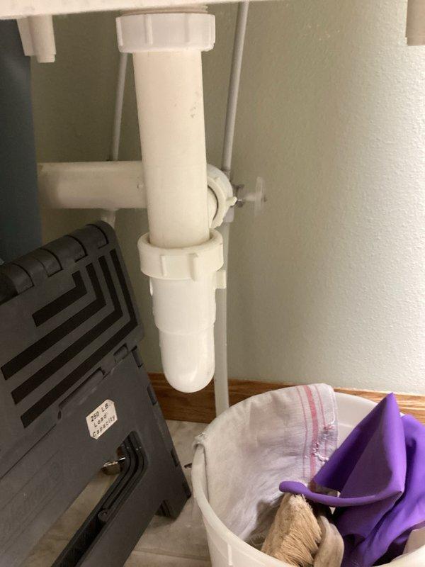 Completed comprehensive plumbing inspection of residential property as part of recurring maintenance program. Documented water heater installation dated June 5, 2023, including copper supply lines, gas connections with yellow-handled shut-off valves, and flexible gas line routing. Identified multiple service needs including bathroom sink drain operating sluggishly due to partial obstruction in P-trap assembly, utility sink faucet requiring valve adjustment or replacement due to stiff operation, and toilet seat needing replacement with ivory standard model. Noted audible squeaking noise originating from plumbing system when shower is activated, likely caused by water hammer or loose pipe mounting. Photographed water heater installation showing proper gas line configuration and under-sink plumbing assembly with PVC drain connections for documentation and future reference.