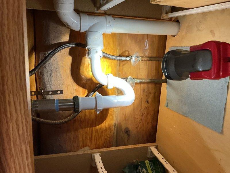 Responded to a call for a continuously dripping bathroom faucet in a corner-mounted pentagonal lavatory sink. Upon inspection, determined the existing 20-year-old two-handle chrome faucet had failed internal components causing the persistent leak. Removed the old faucet assembly and installed a new chrome two-handle lavatory faucet with matching drain assembly. Verified all supply line connections were secure, tested both hot and cold water lines for proper flow and shut-off function, and confirmed no leaks were present at the faucet base or supply connections. The new installation was completed successfully with no further dripping or leakage issues.