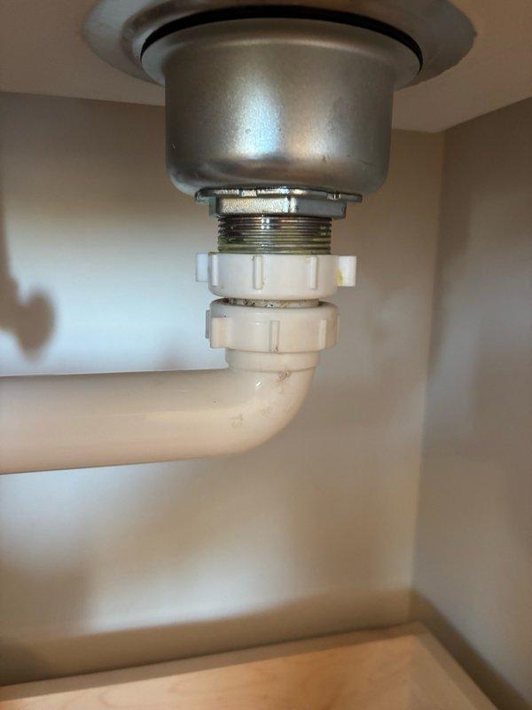 Responded to a kitchen sink leak caused by a broken strainer basket nut on the continuous waste assembly. Replaced the damaged nut, reconnected the drain assembly, and performed thorough leak testing by filling and draining the sink multiple times and running water for over five minutes with no leaks detected. Additionally assessed the laundry tub and faucet for future replacement and provided estimates for that work.