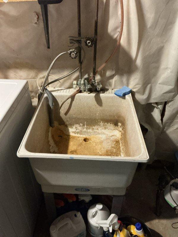 Responded to no hot water call and found Rheem water heater in lockout displaying code 47 error. Successfully reset water heater and restored hot water service to home. Performed biannual plumbing inspection including draining and testing exterior faucets, leak detection throughout property, water heater maintenance and cleaning, sump pump inspection, and laundry hose examination. Inspected utility sink in basement area, noting significant staining and mineral deposits in basin indicating age and wear. Provided estimate for laundry tub replacement due to condition of existing fixture.