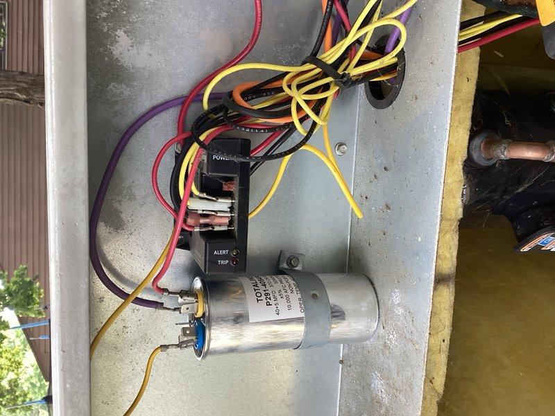 Responded to no cooling complaint on 21-year-old air conditioning system with interior temperature at 80 degrees. Previous technicians had replaced capacitor without resolution, and electrician determined issue was within AC unit rather than breaker. Upon arrival, verified furnace blower operation and confirmed control board signal to condenser. Found condenser breaker tripped and condenser coil blocked with debris. Performed electrical diagnostics on condenser components, reset tripped breaker, and cleared blocked condenser coil. Adjusted TXV bulb positioning and verified refrigerant charge levels within specification. Cycled system through complete operation and confirmed normal cooling function restored.