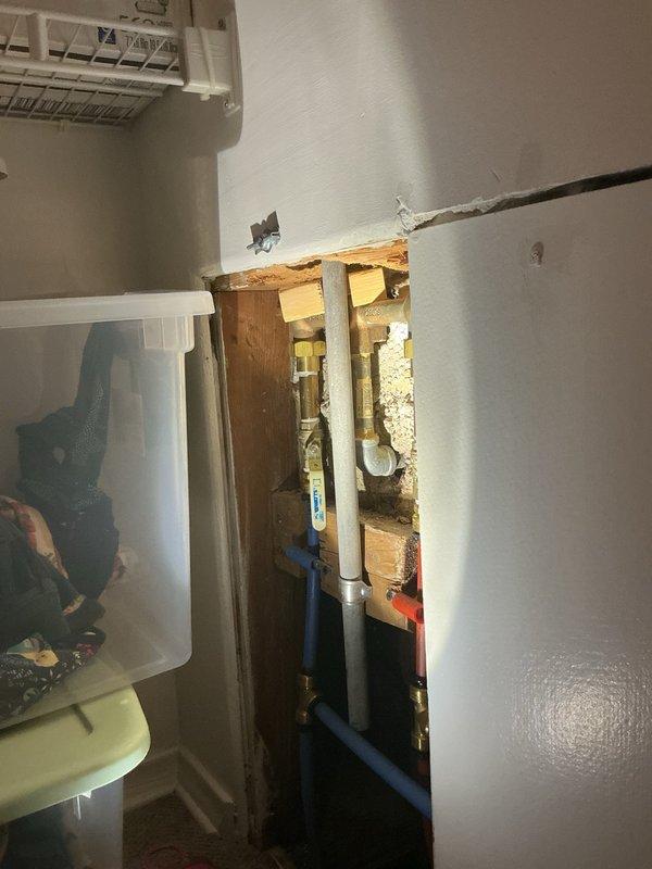 Responded to a leaking shower faucet in a single-family residence with vintage green tile bathroom. Upon inspection, identified active leak at tub spout and cold water valve allowing water passage. Opened wall cavity to access plumbing system, exposing copper supply lines, brass fittings, and shut-off valves behind finished drywall. Assessed valve assembly and determined replacement parts required for proper repair. Completed diagnostic evaluation, documented conditions with photographs, and submitted parts order form to proceed with permanent repair of leaking cold side faucet and tub spout components.