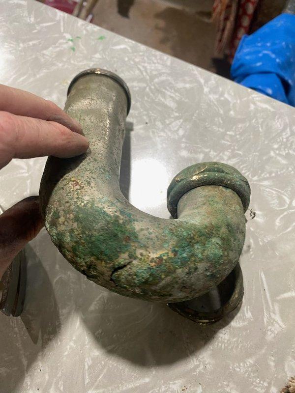 Responded to emergency water leak at laundry sink caused by corroded chrome P-trap that had rusted through completely. The existing metal P-trap assembly exhibited extensive corrosion with green patina and mineral buildup, rendering it unable to maintain a proper seal. Upon inspection, discovered the old fitting had failed due to age-related deterioration and could not be realigned to stop the leak. Removed the compromised metal P-trap assembly and installed new white PVC P-trap with slip-joint connections, restoring proper drainage function and eliminating the water leak. Tested the new installation to confirm leak-free operation, allowing full restoration of water usage for laundry and other household needs.