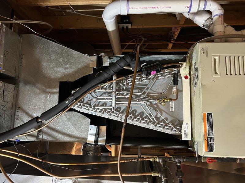 Responded to warranty callback for no cooling and water discharge following recent evaporator coil and TXV replacement. Found refrigerant pressures within specification and no active failures present at time of inspection. Performed airflow diagnostics and system evaluation on aging zone system with deteriorated plenum and damper controls. Basement zone thermostat set to 63° with restricted airflow noted. Unable to duplicate intermittent symptoms; suspect potential blower motor degradation or zone damper malfunction causing periodic issues. System requires monitoring for definitive failure before further repairs can be effectively addressed on this pieced-together installation.