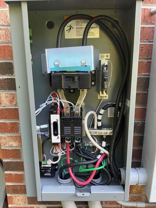Completed generator installation including electrical service panel integration and outdoor equipment setup. Installed transfer switch panel with main circuit breaker, dual branch breakers, and surge protection device with proper wire routing and conduit connections. Connected generator unit to gas supply line via meter, completed all electrical terminations, and verified system operational status.