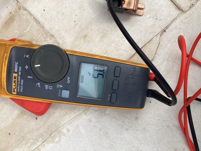 Responded to no cooling complaint on Trane rooftop unit less than 10 years old. Found thermostat calling for cooling with air handler blower operating, but compressor failing to start while condenser fan ran normally. Diagnosed failed run capacitor with multimeter showing open circuit. Replaced defective capacitor, cycled system to verify compressor operation, and confirmed normal refrigerant levels and airflow. System restored to normal cooling operation.