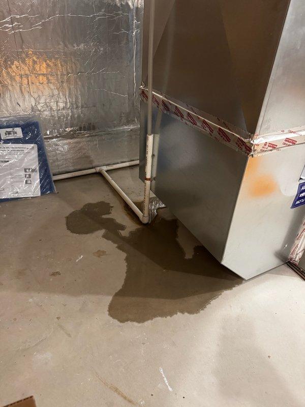 Responded to no cooling complaint with water pooling around furnace area. Found clogged condensate drain line causing water to back up and leak onto basement floor near HVAC equipment. Cleared obstruction from drain line, restored proper drainage flow, and verified system operation. Unit returned to normal cooling function with no further leakage observed.