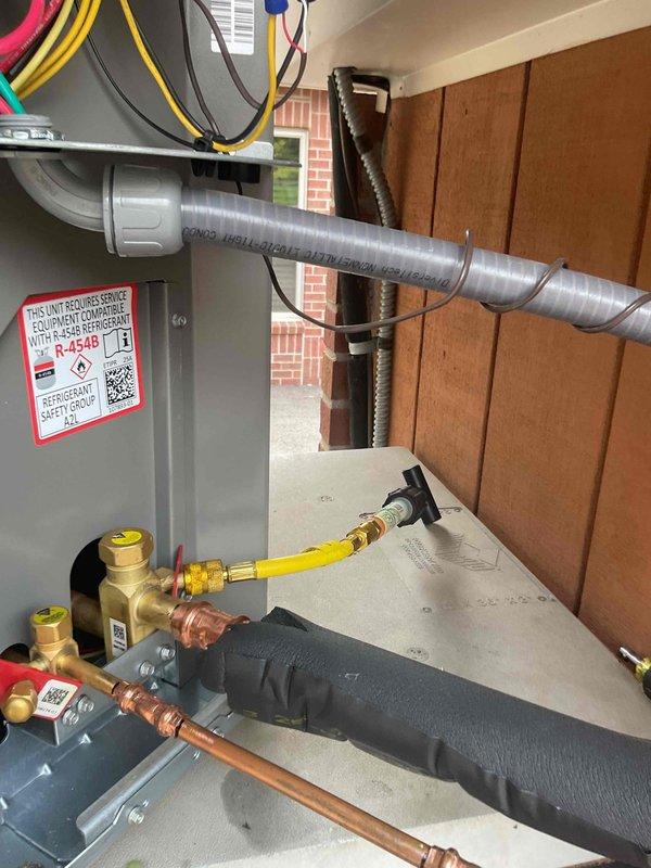 # HVAC Service Completed

Responded to no cooling complaint on residential air conditioning system less than 10 years old. Upon arrival, observed condenser unit short cycling with approximately 10-second run cycles before shutting down. Confirmed system was not providing adequate cooling to structure.

Performed diagnostic evaluation of refrigerant circuit using digital manifold gauges. System pressures indicated critically low refrigerant charge, confirming loss of R-454B refrigerant. Conducted leak inspection of refrigerant lines, coils, and connections. Located refrigerant leak in system requiring repair.

Evacuated remaining refrigerant from system per EPA regulations. Recharged air conditioning system to manufacturer specifications with R-454B refrigerant. Added UV leak detection dye to refrigerant circuit to facilitate future leak identification and monitoring. Verified proper refrigerant pressures on both high and low sides of system using calibrated gauges.

Cycled system throu