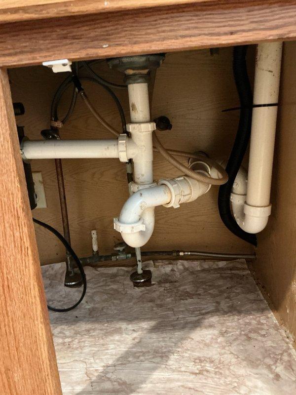 Responded to an active water leak originating from a failing garbage disposal unit beneath the kitchen sink. Upon arrival, confirmed the existing disposal was the source of the leak, which had been temporarily contained by the customer. Removed the old defective garbage disposal unit from the sink mounting assembly. Installed a new garbage disposal unit with electrical cord, ensuring proper alignment with the sink drain flange and secure mounting. Connected the discharge pipe to the existing drain line configuration. Completed all electrical connections and verified proper operation of the new unit. Performed a comprehensive leak test by filling the sink and running water through the disposal while checking all connection points and seals. Confirmed no leaks were present at the mounting flange, discharge connection, or any plumbing joints. Verified full functionality of the disposal unit. Left the workspace clean with all connections secure and the system operating properly.