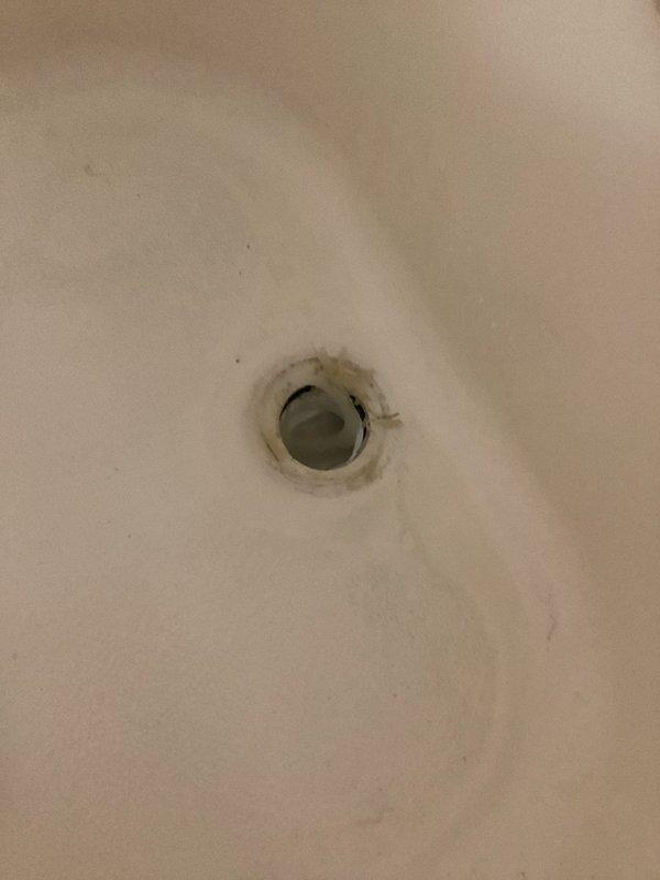 Responded to water leak originating from bathtub drain, causing water damage to ceiling of downstairs unit. Upon inspection, determined that drain was leaking when tub was filled with water. Removed existing drain assembly, cleaned drain opening of previous sealant residue, and reinstalled drain using plumber's putty to create proper watertight seal, resolving the leak issue.