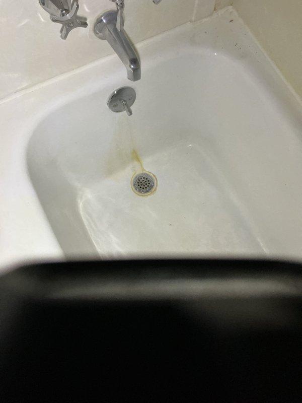 Responded to emergency plumbing call for active leak at bathtub drain assembly requiring immediate attention. Upon arrival, found customer using bucket to collect water from failing tub waste and overflow system. Performed complete replacement of tub waste and overflow assembly per approved estimate. Removed existing deteriorated drain components showing significant mineral buildup and corrosion around drain opening. Installed new standard tub waste and overflow assembly, ensuring proper seal and alignment. Tested system for leaks and verified proper drainage function. Emergency repair completed successfully, eliminating active water leak.