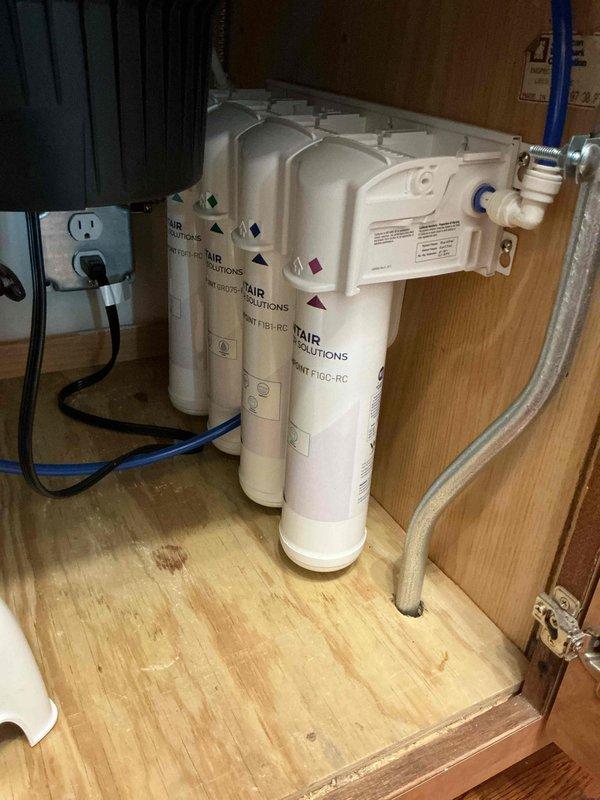 Responded to service call for reverse osmosis filter replacement on a four-stage under-sink water filtration system. Upon arrival, inspected the existing RO system consisting of three white cylindrical filter cartridges mounted vertically on a manifold assembly. After assessment and pricing discussion, customer declined to proceed with the filter replacement service. No work was performed on the filtration system, and dispatch fee was waived.