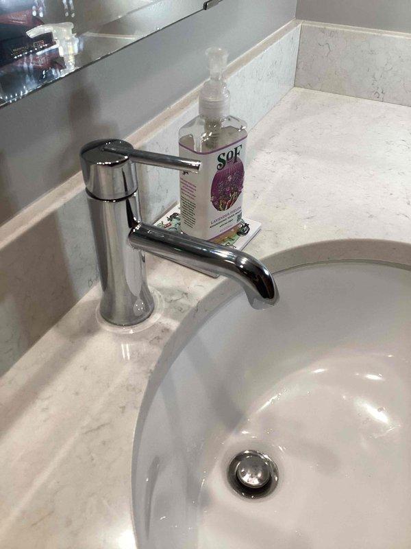 Responded to service call regarding chemical odor emanating from bathroom faucet and water supply installed approximately one year prior. Inspected Delta single-handle chrome faucet assembly, supply lines, and drain connections for potential defects or contamination sources. Contacted manufacturer technical support to assess warranty coverage for suspected defective components causing water odor issue. Documented faucet installation with photographs showing complete fixture assembly, countertop mounting, and surrounding conditions for manufacturer warranty claim submission. Warranty claim was denied by manufacturer. Provided technical assessment and photographic documentation to facilitate replacement faucet procurement through manufacturer channels.