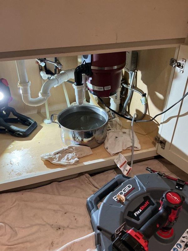 Responded to a backed-up kitchen sink that was overflowing into the cabinets. Upon arrival, accessed the drain line beneath the sink and utilized a RIDGID flex-shaft machine to clear the blockage. Removed significant accumulation of grease and hair from the kitchen drain line, restoring proper drainage and flow to the sink.