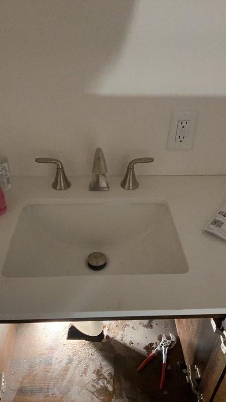 Completed installation of bathroom and utility sink fixtures during scheduled service call. Set and secured brushed nickel three-piece faucet assembly with dual lever handles and central spout on undermount white basin, ensuring proper alignment and water flow. All fixtures tested for leaks and functionality upon completion.